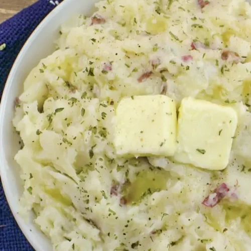 A bowl of creamy southern mashed potatoes garnished with herbs