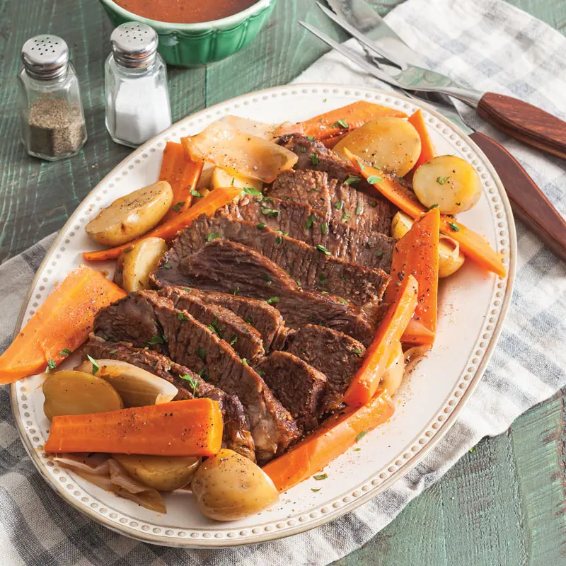 A steaming dish of Sunday pot roast with vegetables.